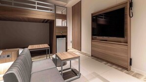 A modern living room with a sofa, a coffee table, a TV mounted on a wooden panel, and a built-in wardrobe.