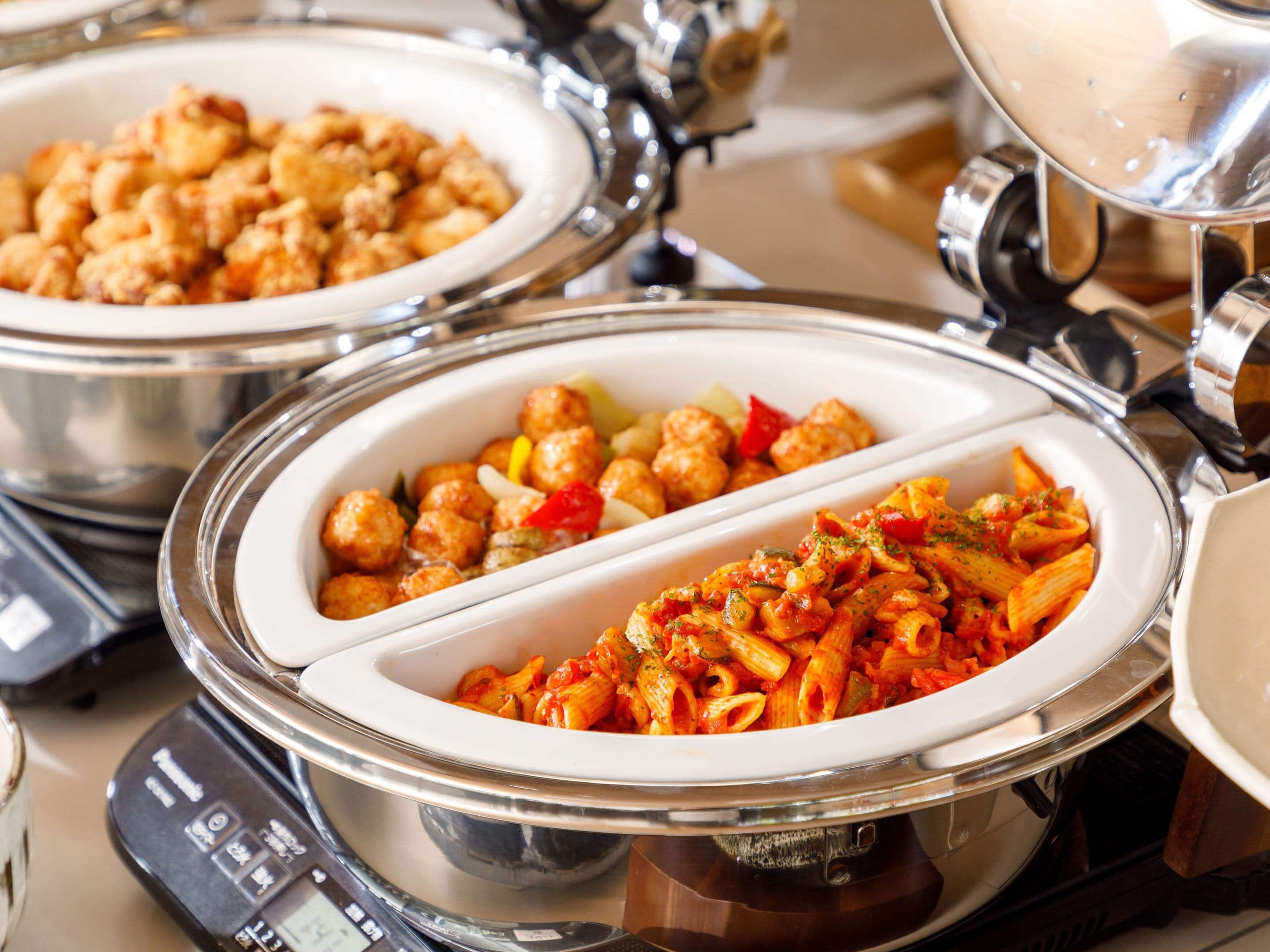 A buffet with pasta and meat dishes.