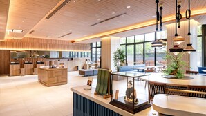 A modern hotel lobby with a reception desk, seating area, and large windows.
