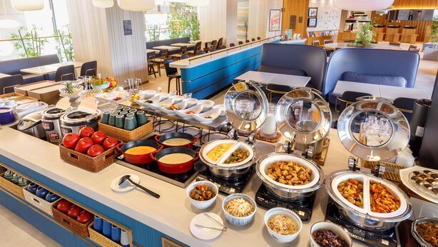 A buffet with various dishes and utensils, a seating area with tables and chairs, and a counter with a blue accent wall.