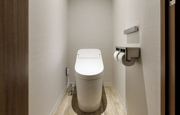 Un baño moderno con inodoro, dispensador de toallas de papel y secador de manos.