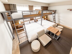 Une chambre avec un lit superposé, un bureau et un coin salon.
