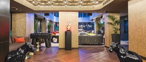 A lobby with a wooden floor, a pool table, and two black dog statues.