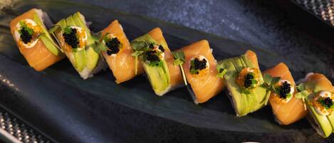 A sushi platter with nigiri and a small bowl of soy sauce.