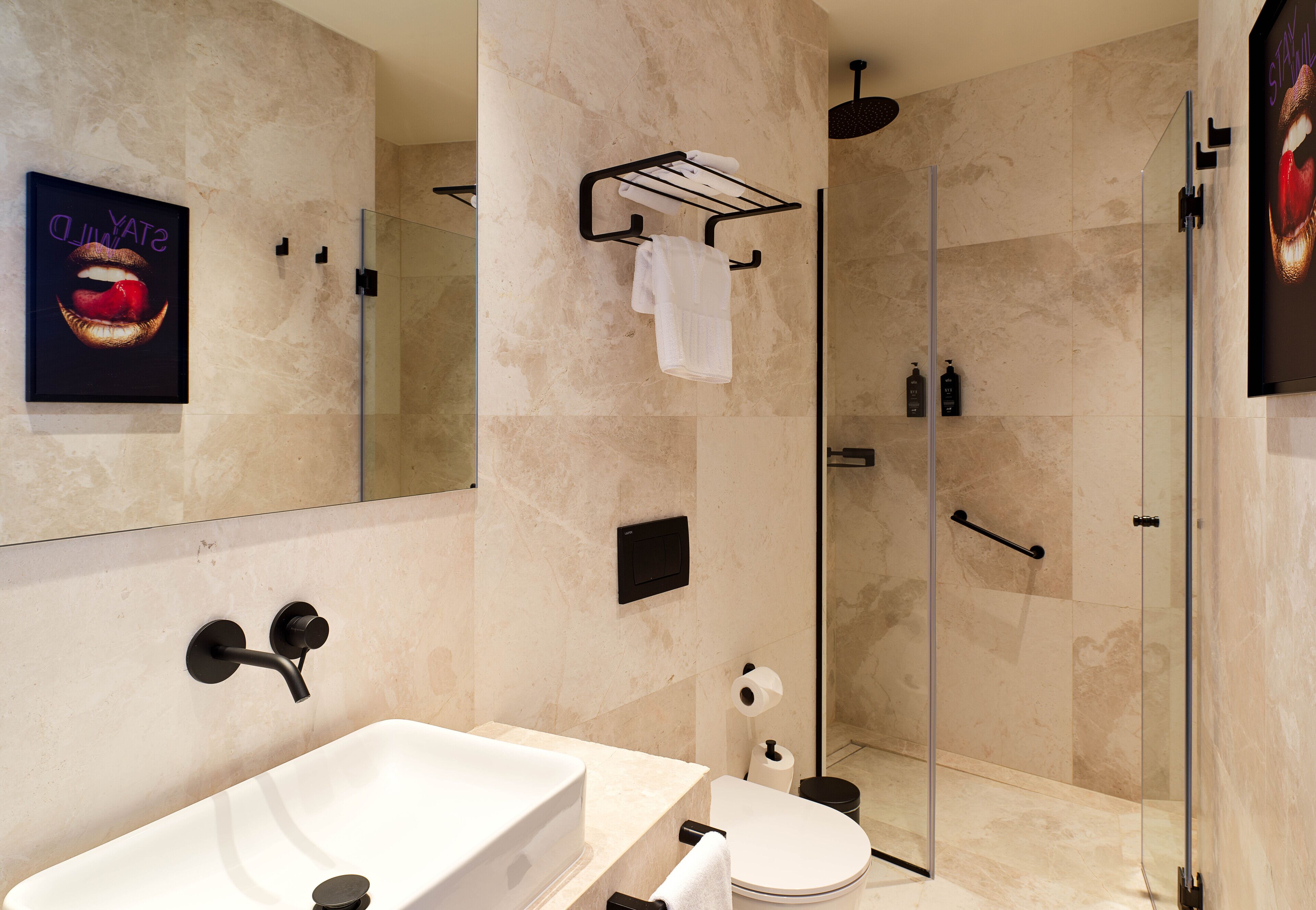 A modern bathroom with a large sink, a glass shower enclosure, and a toilet.