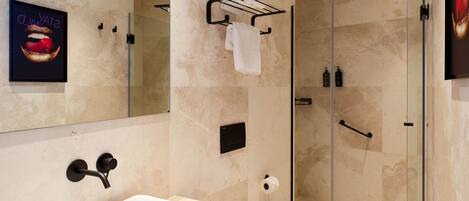 A modern bathroom with a large sink, a glass shower enclosure, and a toilet.