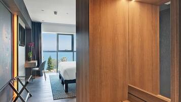 Habitació d'hotel moderna amb una finestra gran, un llit, una taula de treball i una cadira.