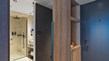 Un baño moderno con cabina de ducha de vidrio, tocador de madera y puerta azul.