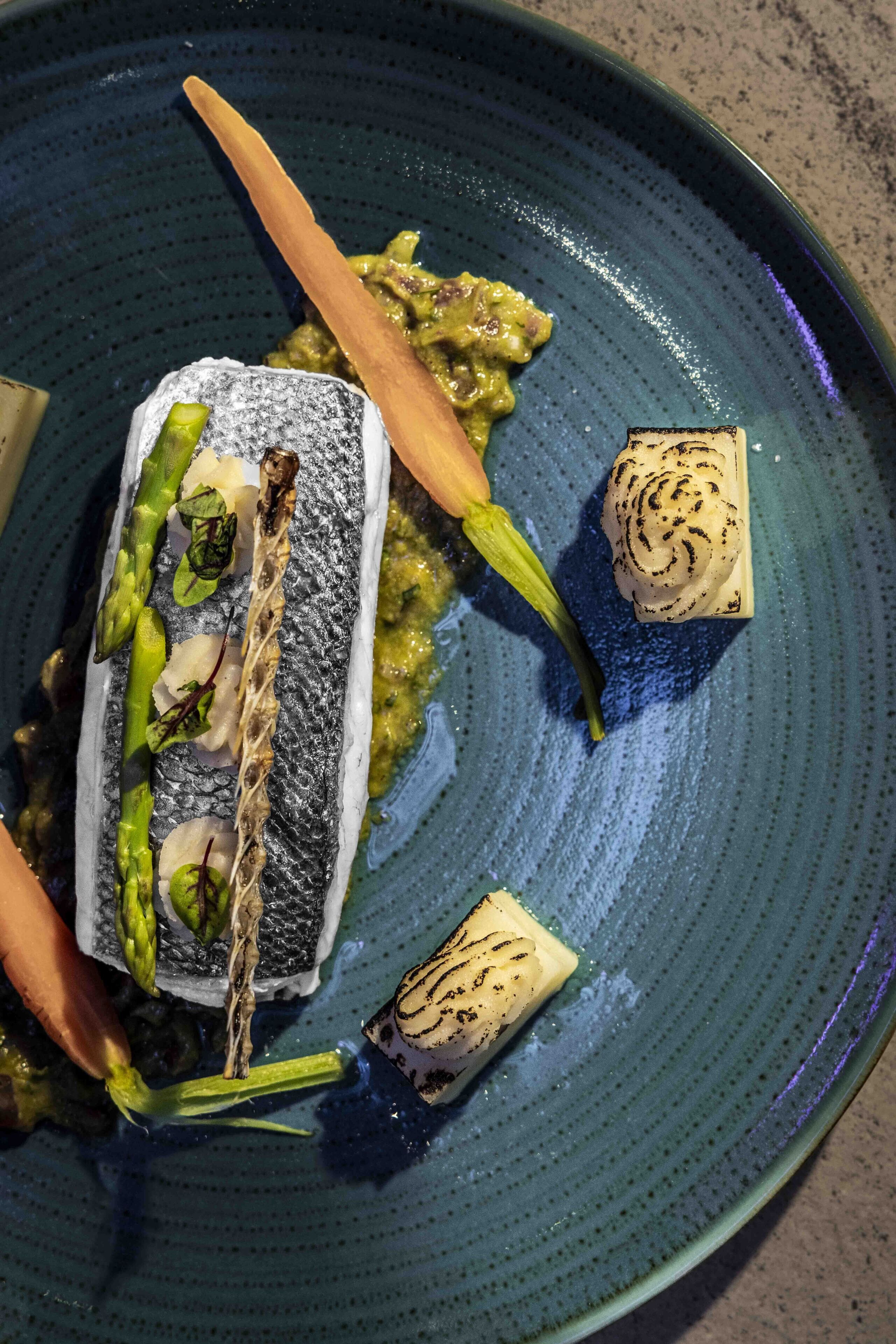 A plate with a fish fillet, asparagus, and a small piece of bread.
