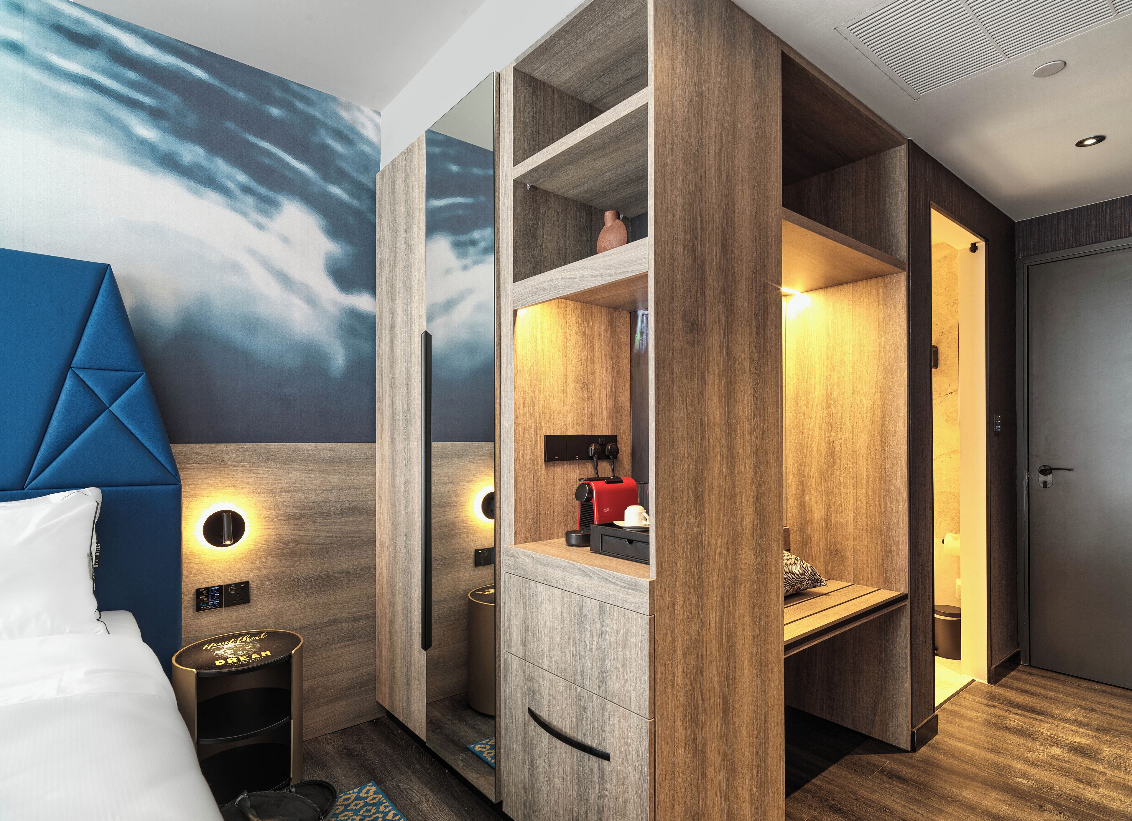 Ett modernt hotellrum med en stor säng, ett skrivbord, en garderob och ett badrum.