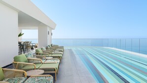 Zona de piscina en la azotea con mobiliario de mimbre y vistas despejadas al océano.