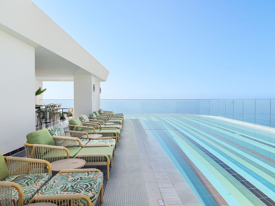Una piscina al aire libre, sombrillas, sillones reclinables de piscina