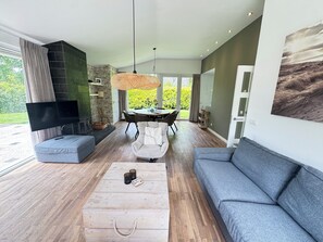 Een moderne woonkamer met een bank, salontafel, televisie en een eethoek.