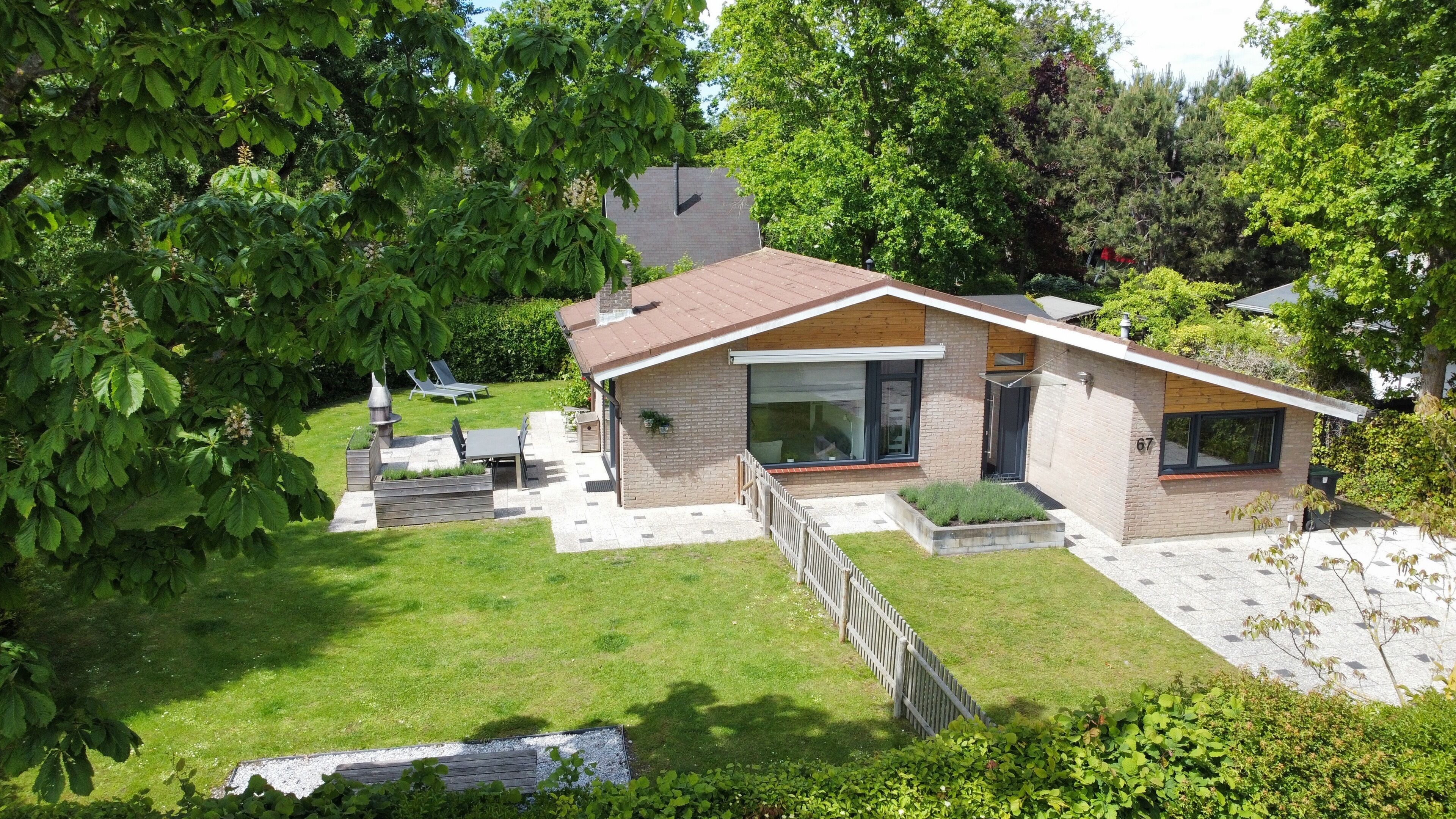 Une maison moderne avec une façade en briques, de grandes fenêtres et une pelouse bien entretenue.