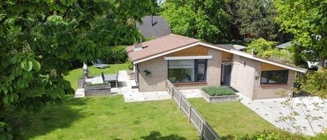Une maison moderne avec une façade en briques, de grandes fenêtres et une pelouse bien entretenue.