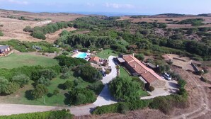 A rural property with a swimming pool, a long driveway, and a large house with a tiled roof.