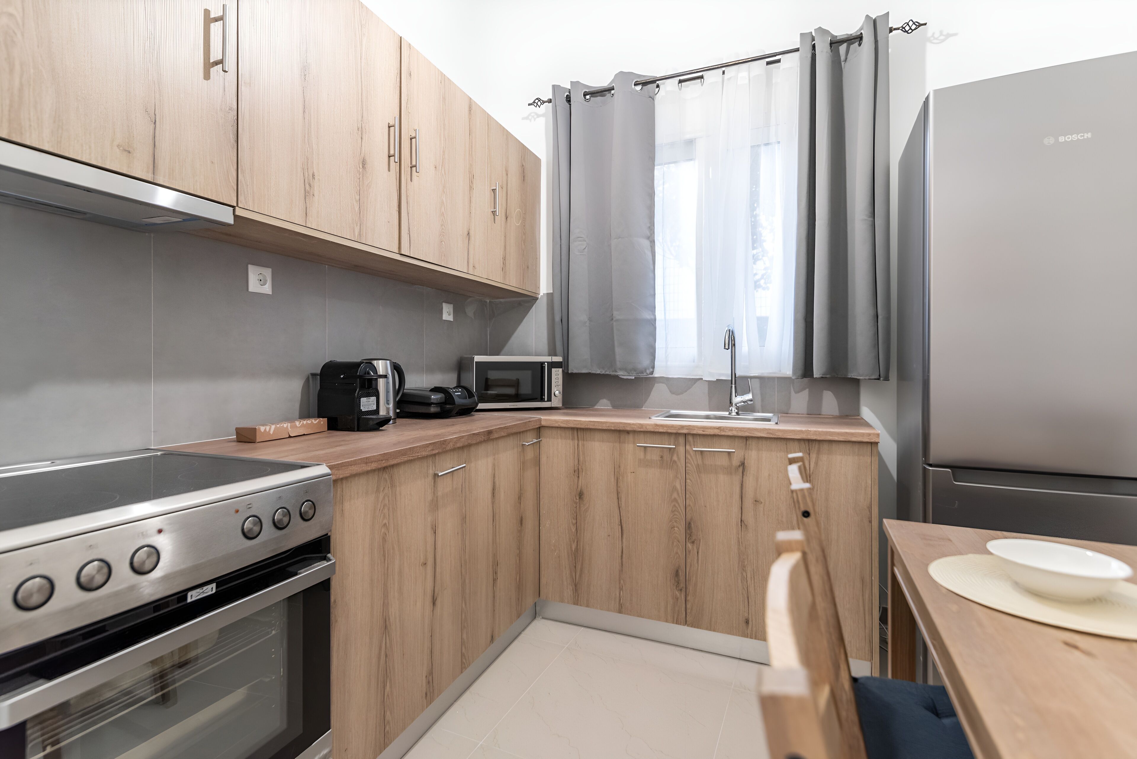 A compact kitchen with wooden cabinets, a stainless steel stove, a microwave, and a refrigerator.
