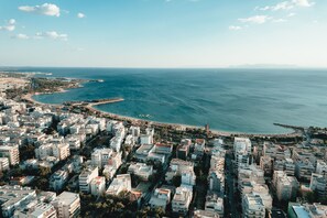 An aerial view of a coastal city with dense urban development, a prominent waterfront, and a clear sky.
