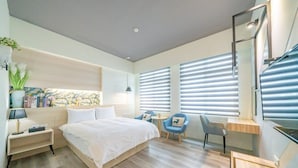 Una habitación de hotel moderna con una cama grande, un escritorio, dos sillas y un ventanal con persianas.