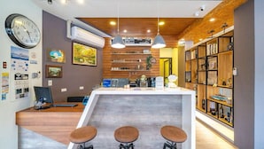 Una cocina moderna con una isla central, taburetes de bar, iluminación colgante y una estantería de madera.