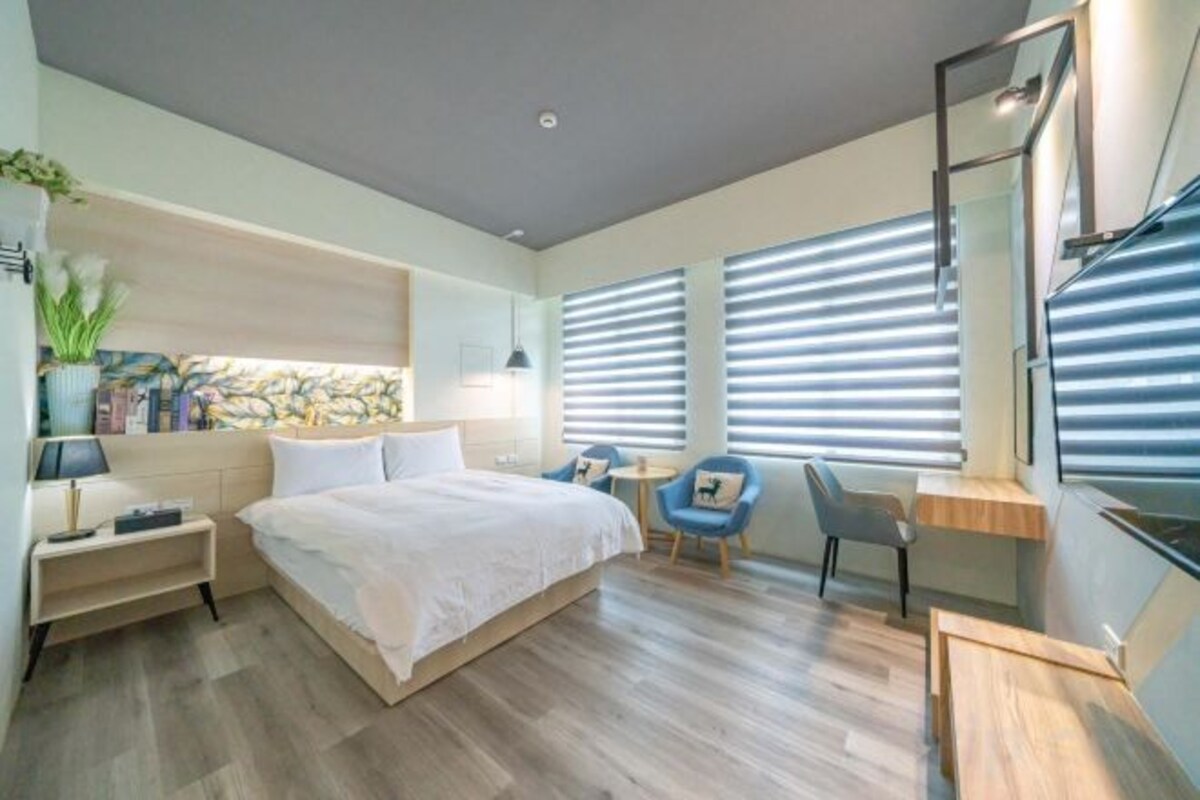 A modern bedroom with a large bed, bedside tables, a desk, and a chair.