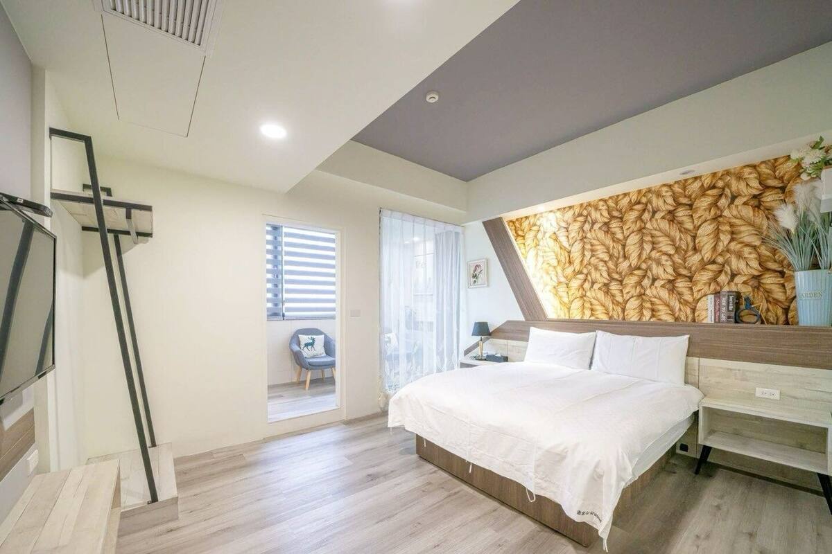 Une chambre à coucher moderne avec un grand lit, un téléviseur fixé au mur et un plancher en bois.