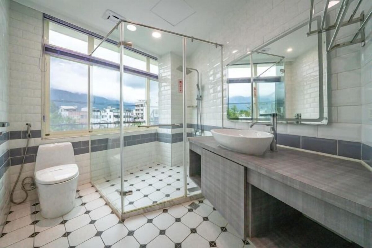 A modern bathroom with a glass-enclosed shower, a large sink, and a toilet.