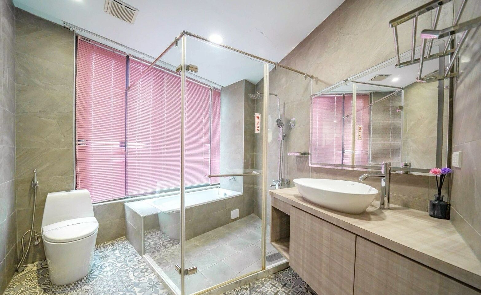 Un baño moderno con ducha de vidrio, inodoro blanco, lavamanos grande y espejo.
