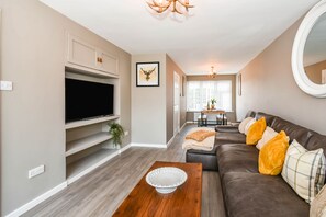 Relax in this stylish living room with a flat-screen TV, comfortable sofa, and dining area.