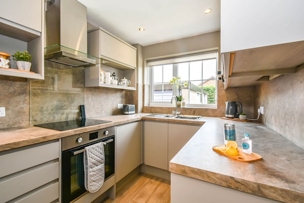 Enjoy cooking in this well-lit kitchen with a sink, stainless steel range hood, and ample counter space.