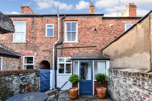 Traditional brick building with a charming entrance, complete with a blue door and white-framed windows.