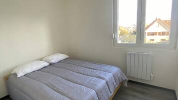 Un dormitorio con cama, ventana y radiador.