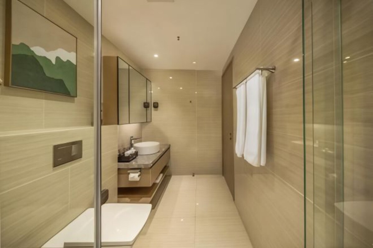 Un baño moderno con cabina de ducha de vidrio, un espejo grande, un lavabo y un perchero para toallas.