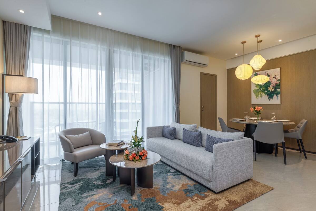 Un salon moderne comprenant un canapé, deux fauteuils, une table basse et un coin repas avec une table et des chaises.