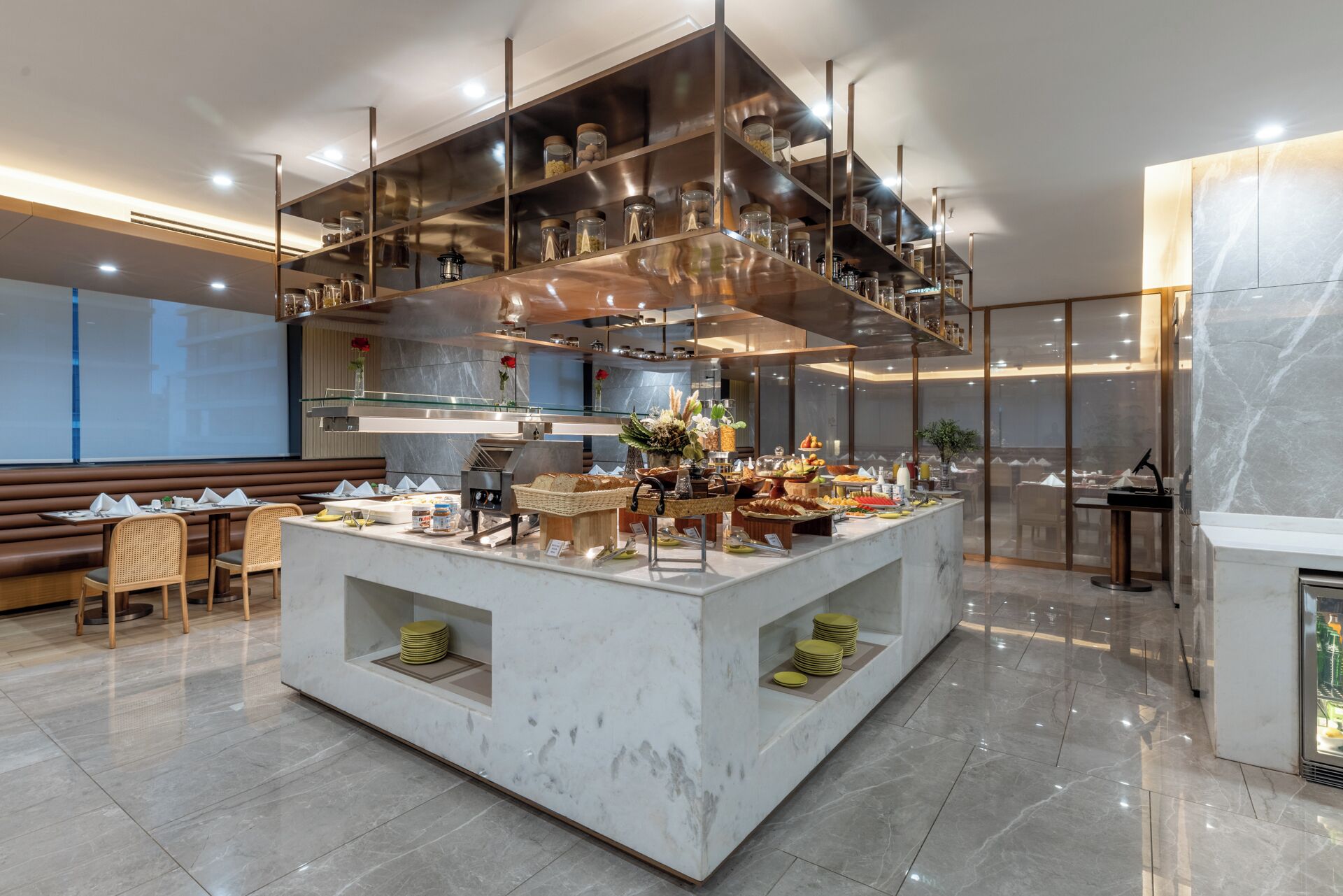 A modern breakfast bar with a marble countertop, glass shelving above, and a seating area with wooden chairs and a bench.