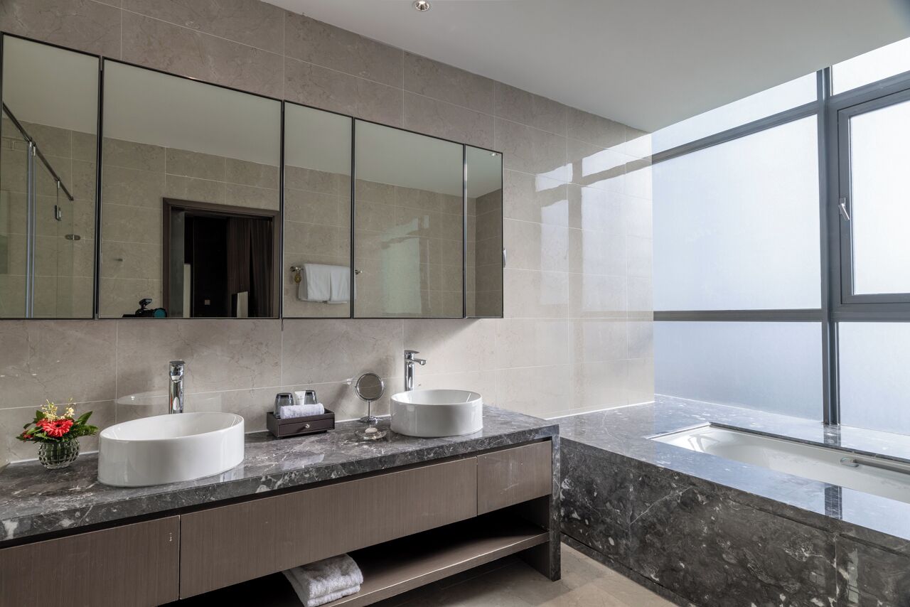 A modern bathroom with two sinks, a large mirror, and a window providing natural light.