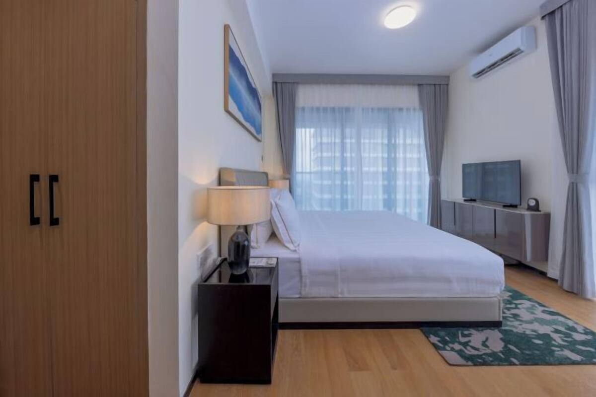 Une chambre d’hôtel équipée d’un lit, d’une table de chevet, d’une lampe, d’un téléviseur et d’un appareil de climatisation.