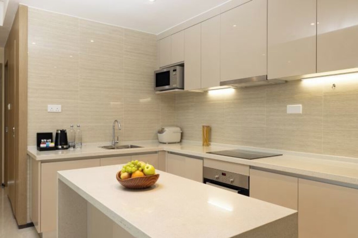 Una cocina moderna con microondas, pileta y un bol de fruta en la encimera.