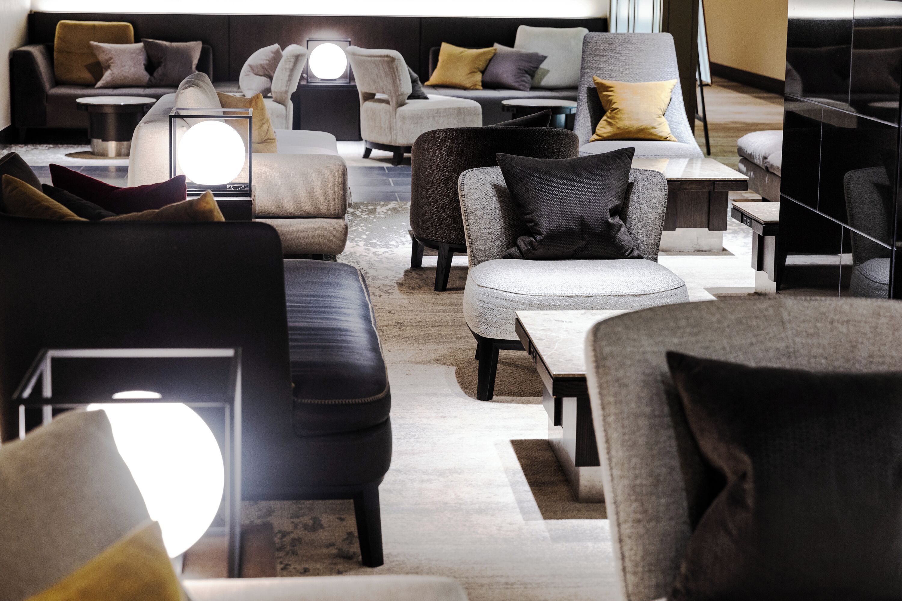 A modern interior with multiple seating areas, including sofas and armchairs, arranged around a central coffee table.