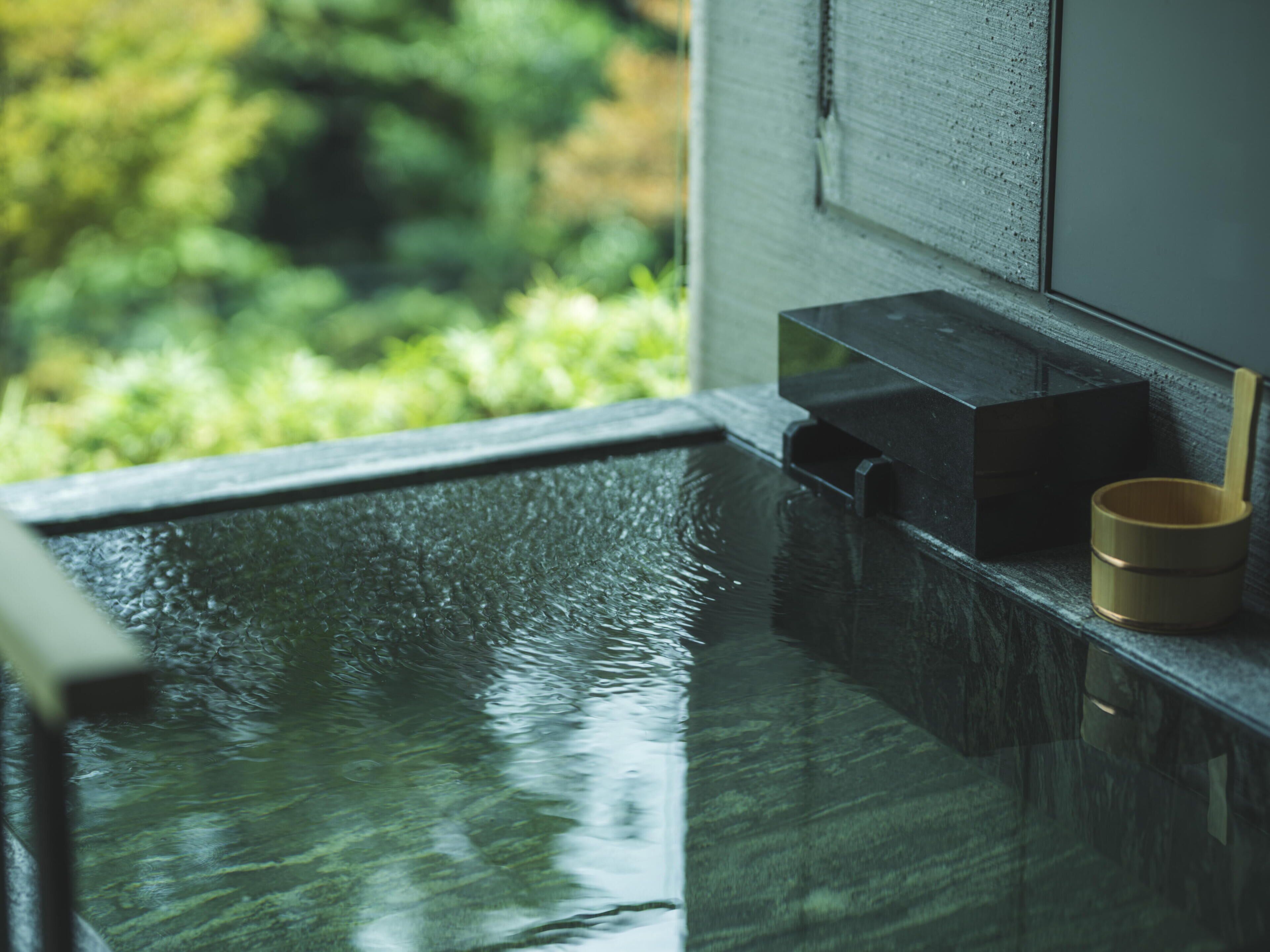 A bathroom with a glass-enclosed shower, a wooden cup, and a towel rack.