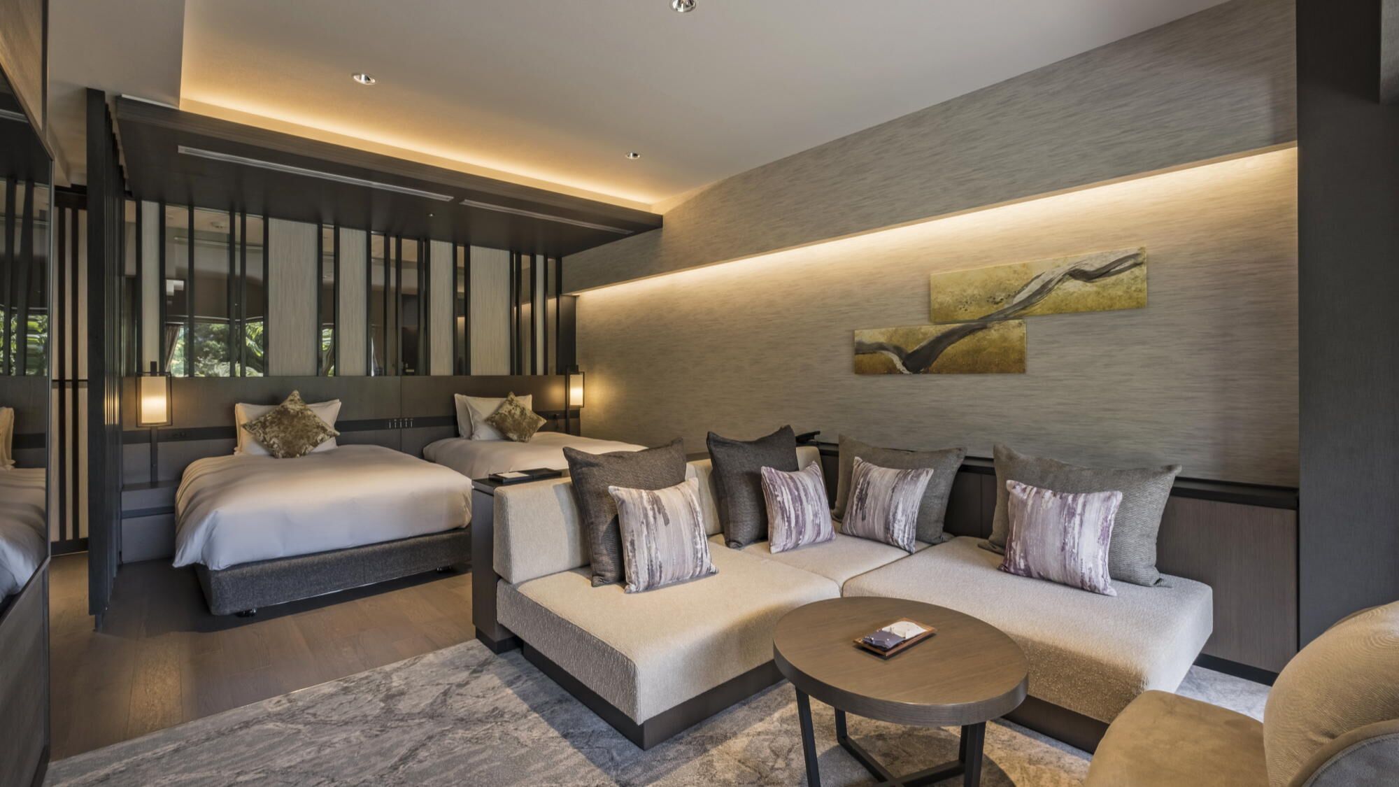 Een moderne hotelkamer met twee bedden, een bank, een bijzettafeltje en een groot raam.