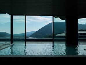 Piscina interior moderna con vistas a montañas a través de amplios ventanales.