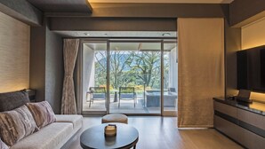 A modern living room with a sofa, a round table, and a large TV. - Hakone Gora KARAKU (ORIX HOTELS & RESORTS) (Hakone)