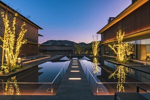 Un edificio moderno con un estanque reflectante y árboles iluminados.