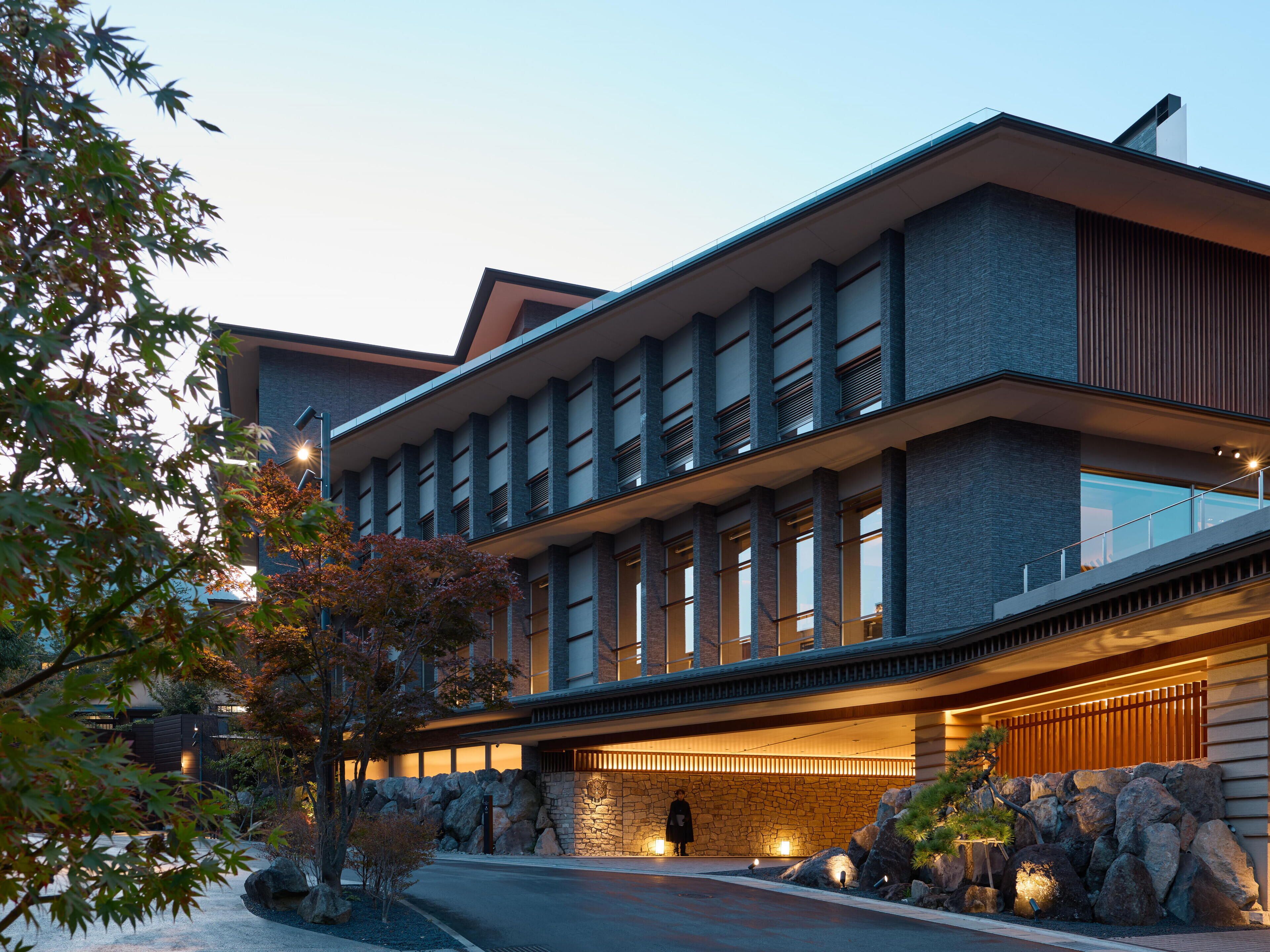 A modern building with a stone facade, large windows, and a stone wall entrance.