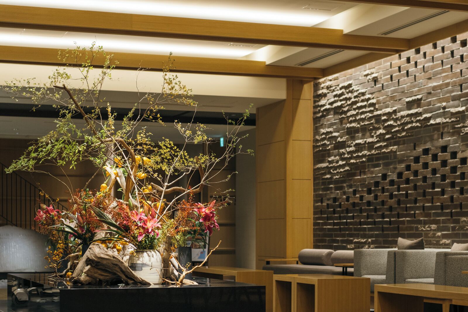 A modern interior with a seating area, a decorative plant arrangement, and a textured wall.