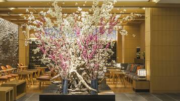 A lobby with a central floral arrangement, seating areas, and a brick wall.