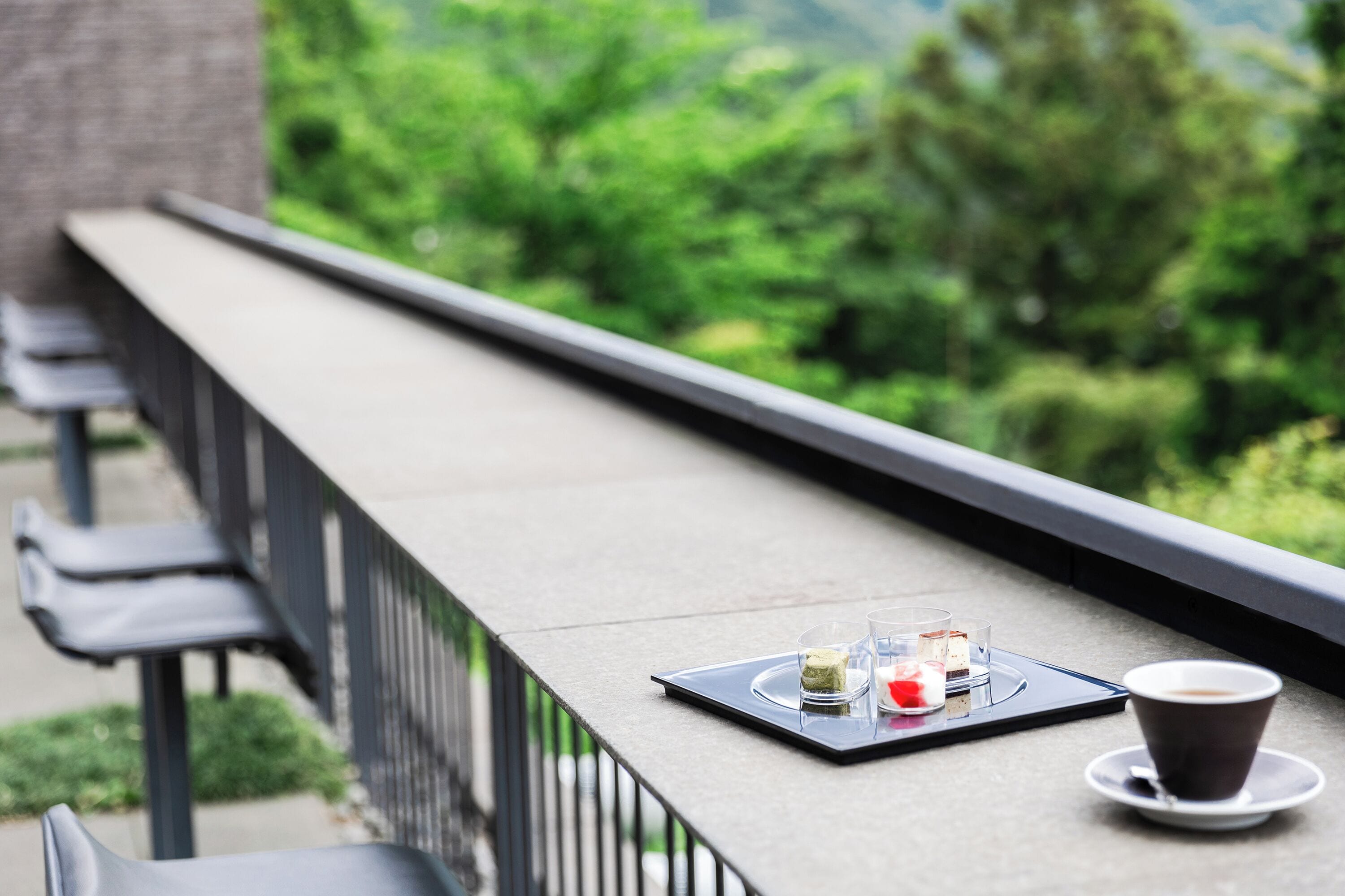 En balkon med et bord dækket til to personer, med en kop kaffe og et dessertfad.