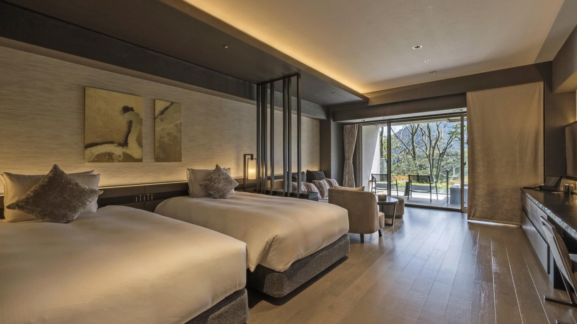 Een moderne hotelkamer met twee bedden, een zithoek en een groot raam met uitzicht.