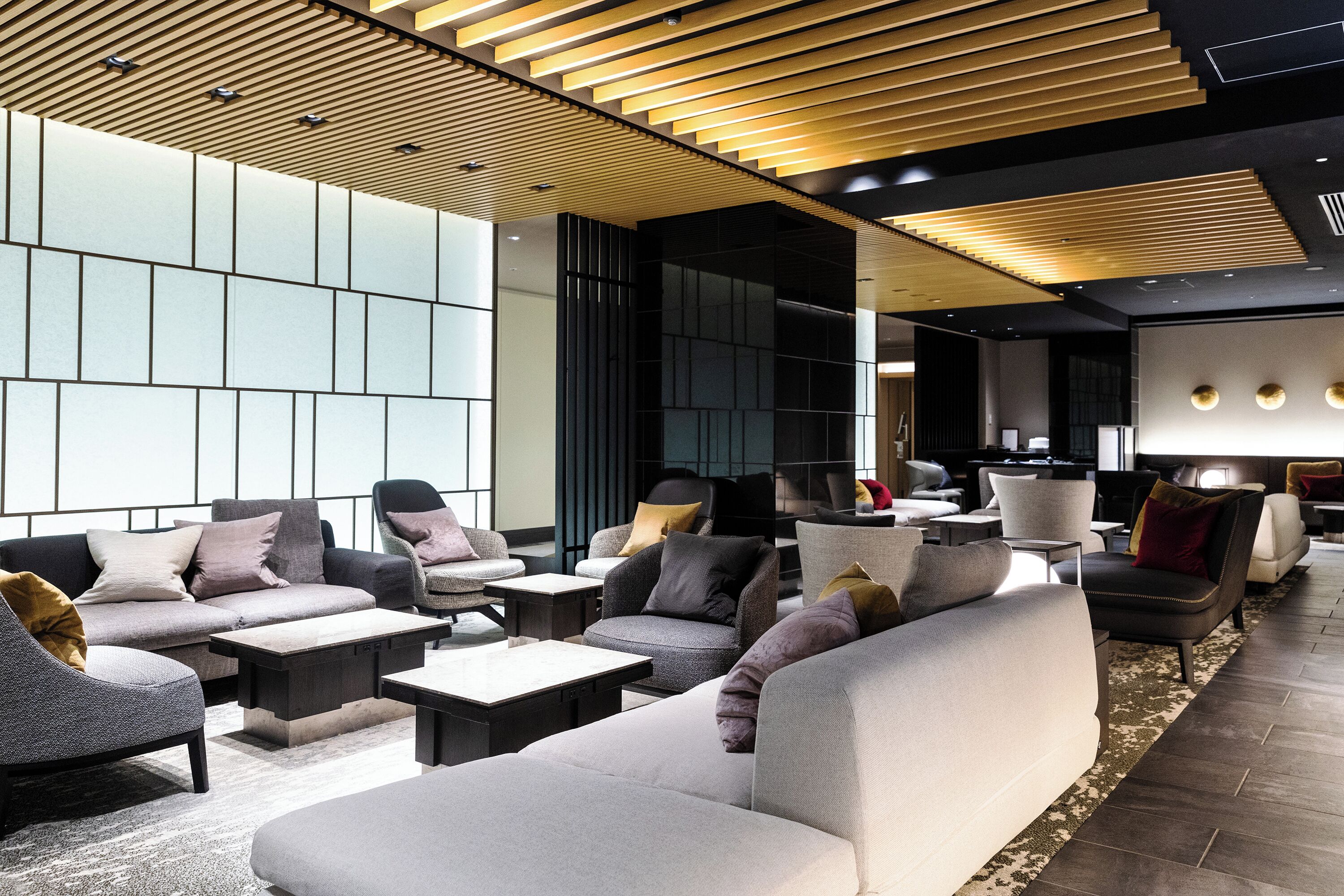 A modern lounge area with sofas, armchairs, and tables arranged for socializing.